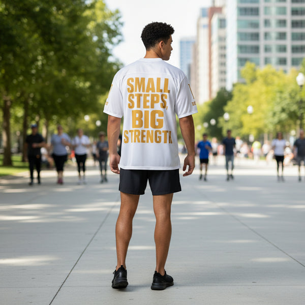 Person wearing a white t-shirt with 'Small Steps Big Strength' text on the back, on a white background